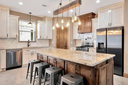 Modern kitchen with white cabinets, granite island, pendant lights, and stainless steel appliances