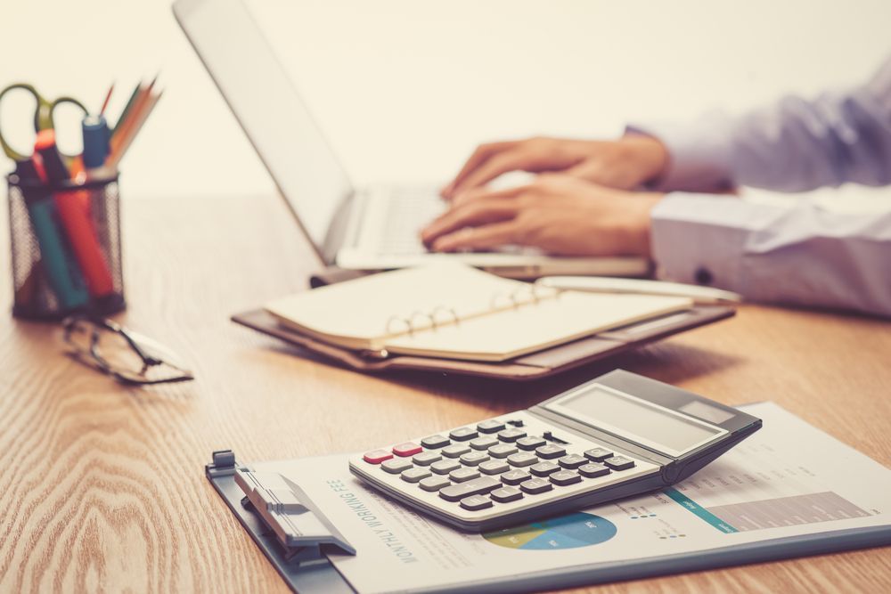 A Person is Typing on a Laptop Next to a Calculator on a Clipboard — Adding Value CFO Pty Ltd in Palmerston, NT