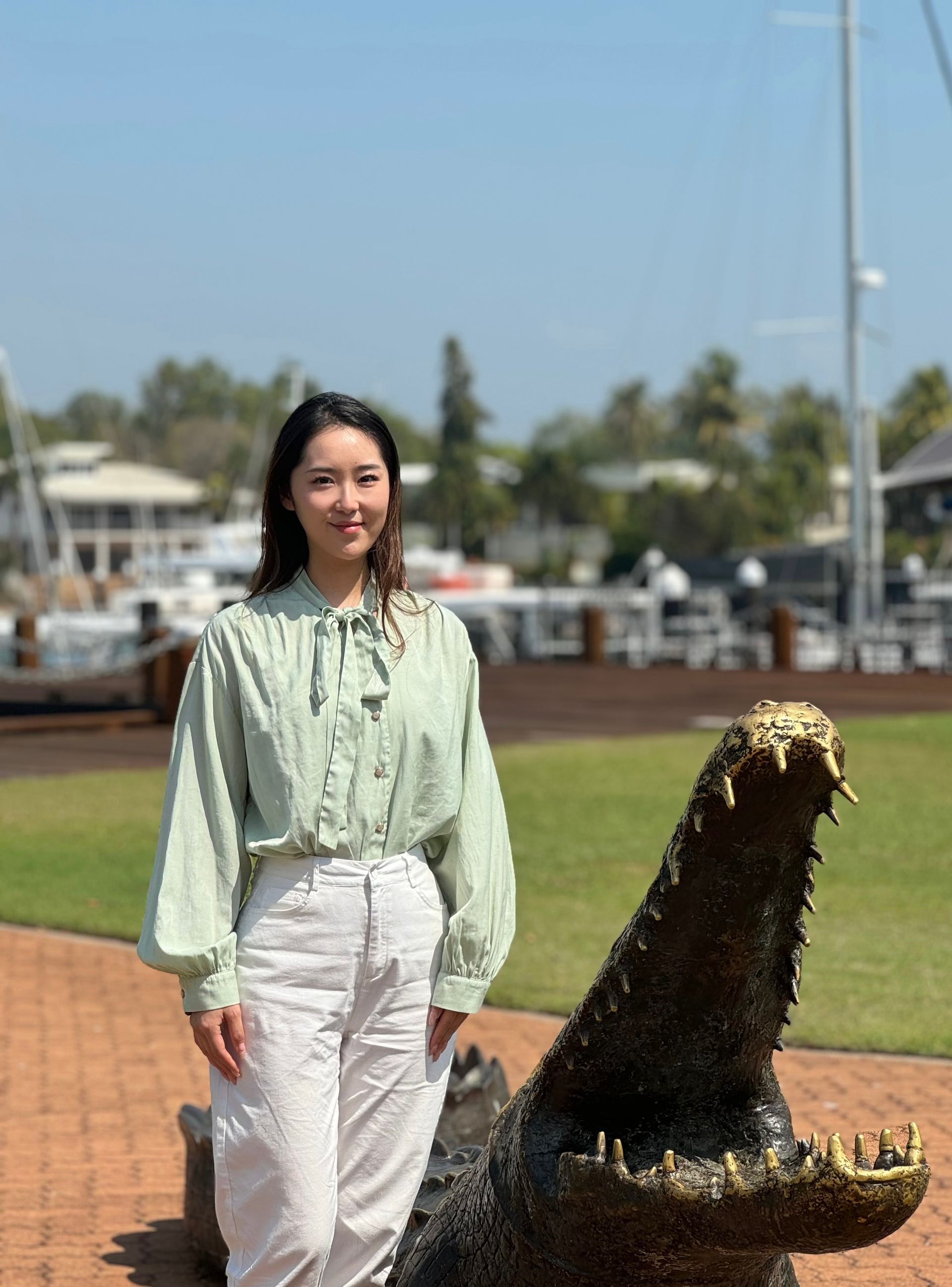 A woman is standing next to a statue of a crocodile.