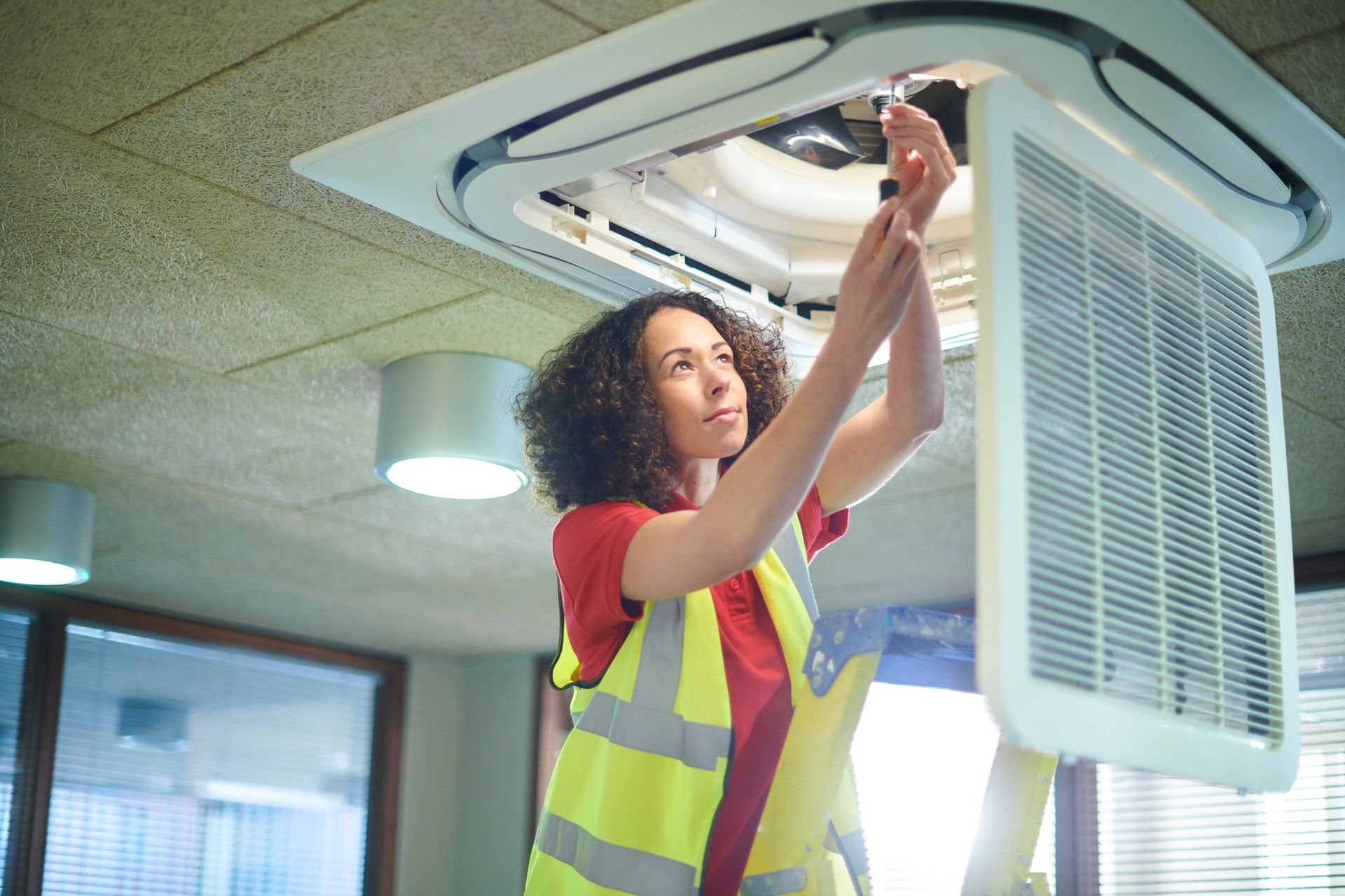 Technician in Safety Vest Repairing a Ceiling Air Conditioner Unit — Enterprise Air That's Cool In Svensson Heights, QLD