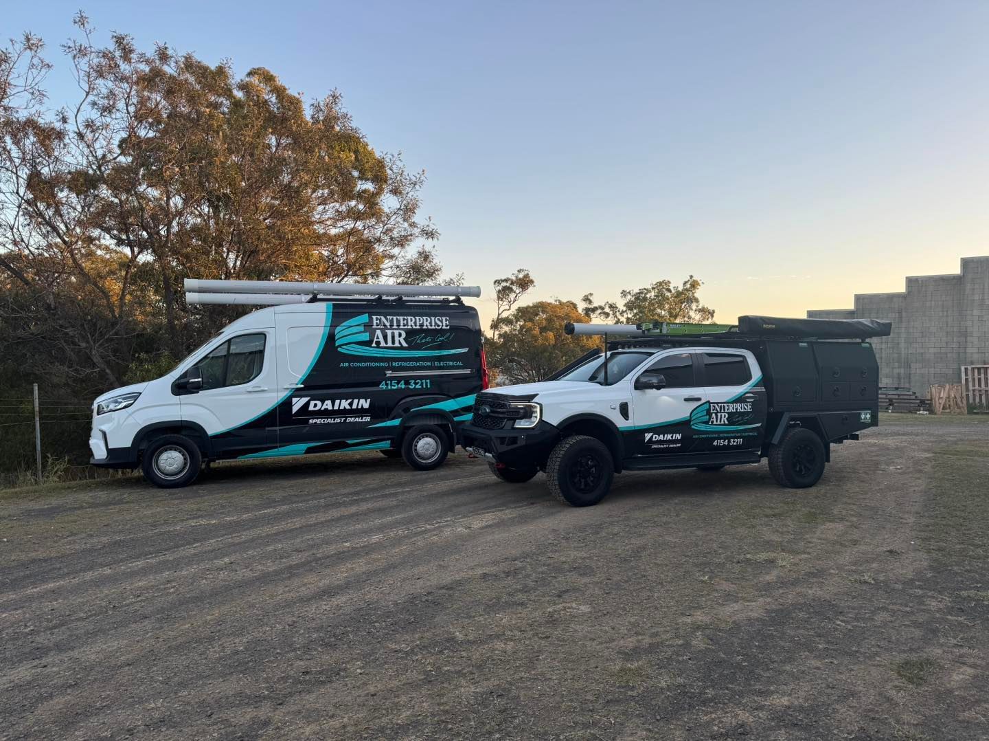 Two White-And-Teal Work Trucks Parked on Grass— Enterprise Air That's Cool In Svensson Heights, QLD