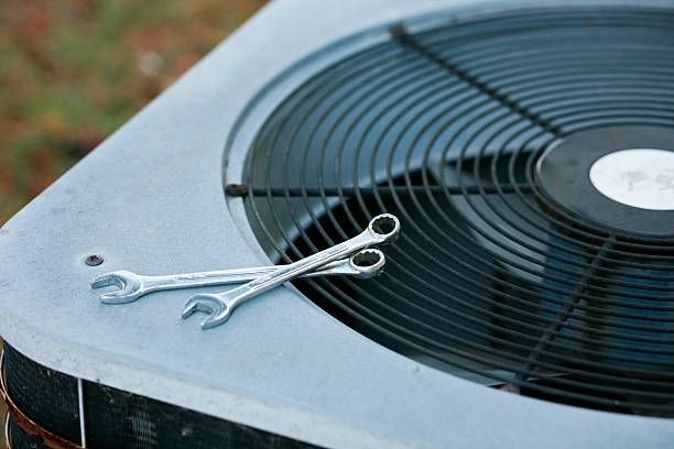 Two Wrenches Resting on a Metal Air Conditioner Unit Grille — Enterprise Air That's Cool In Svensson Heights, QLD
