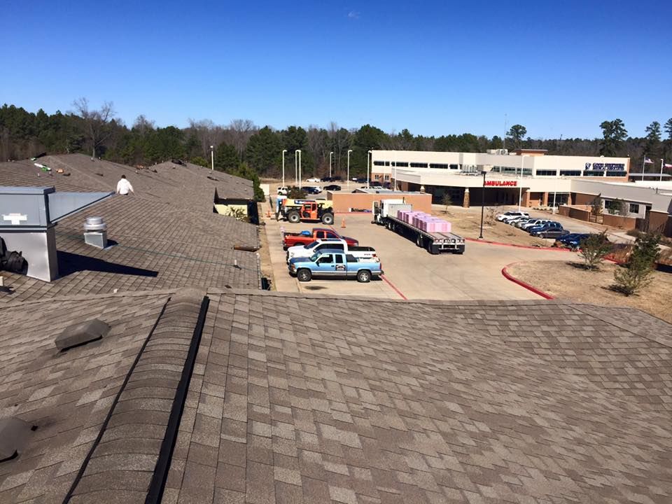Construction site with trucks on a rooftop and building in background. Blue sky, sunny day.