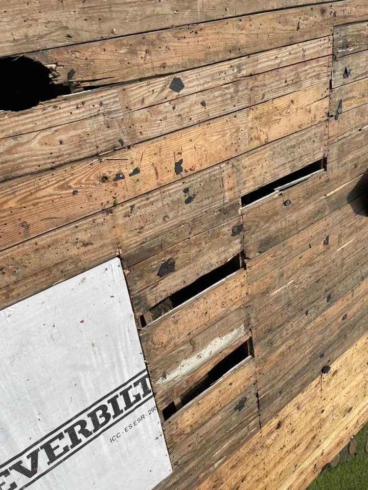 Damaged wooden roof with multiple holes, showing old boards and exposed underlayment.