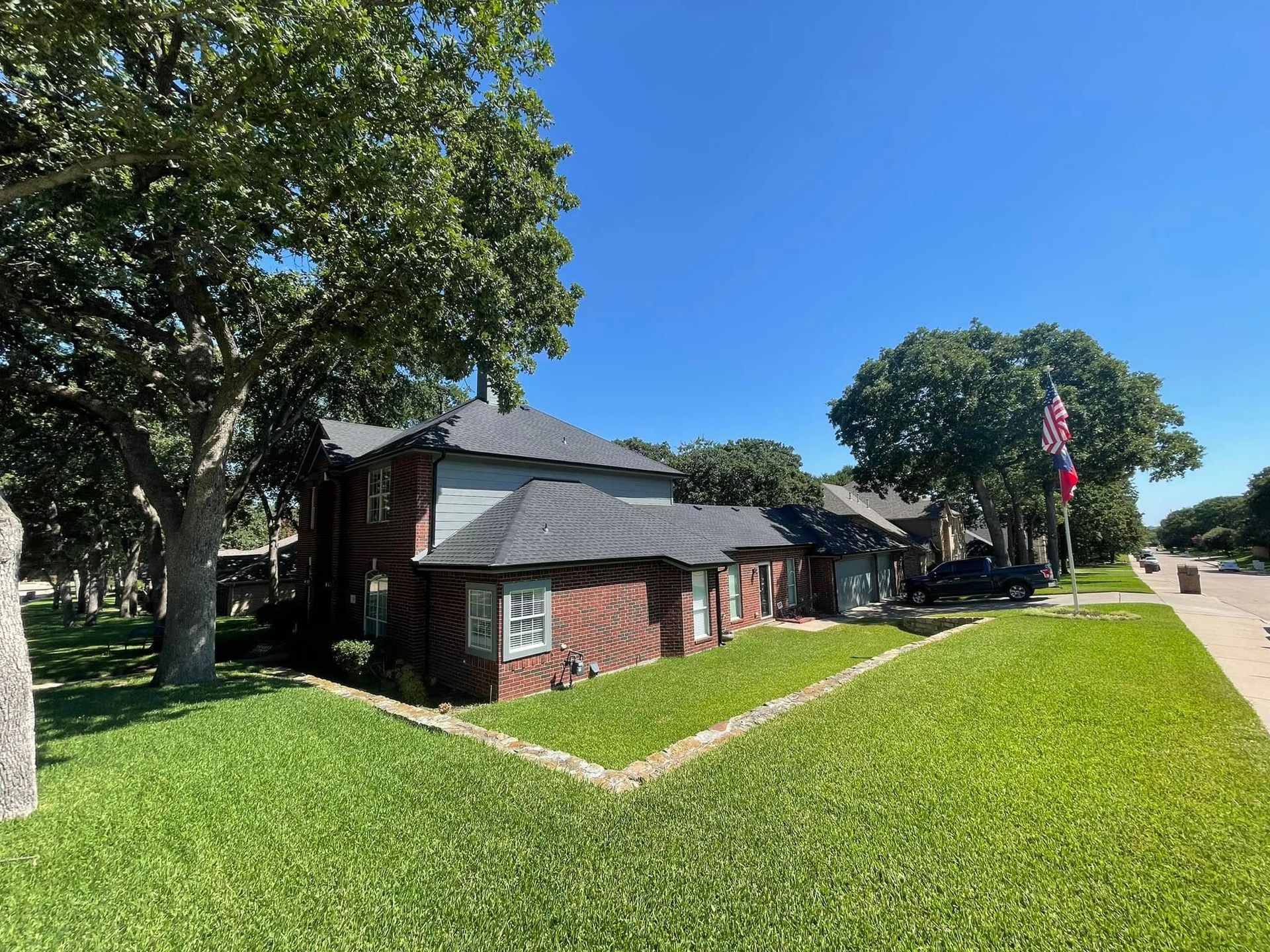 Brick building with green lawn, trees, and an American flag under a blue sky.