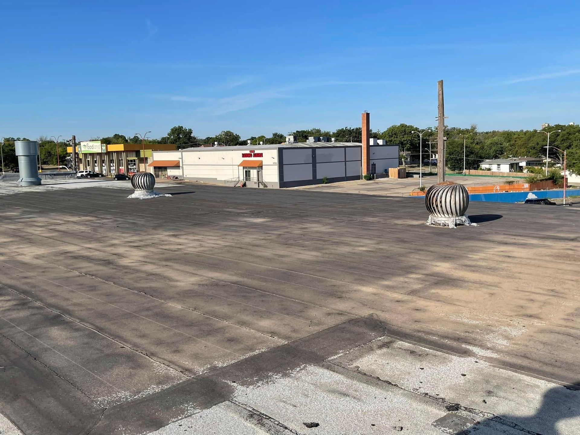 View of a large, empty parking lot with a building in the distance on a sunny day.