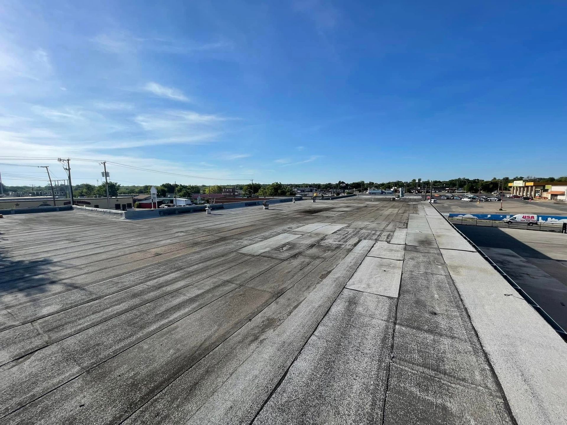 View of a large, gray surface being prepped for paving, under a bright blue sky.