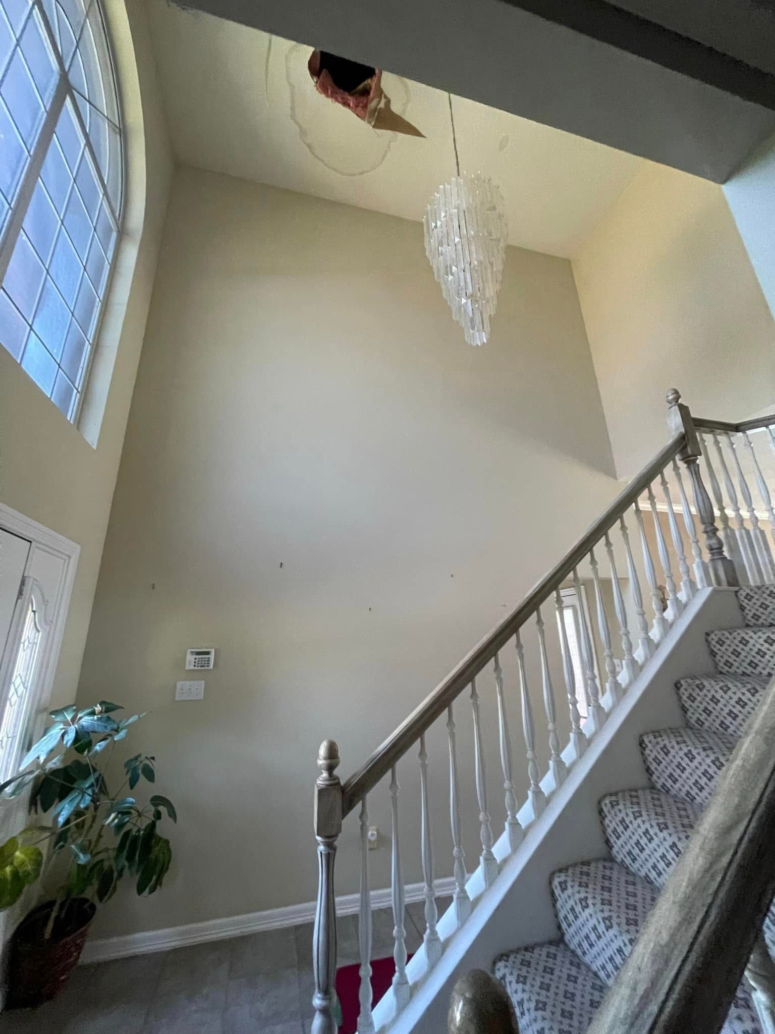 High-ceilinged entry with stairs and chandelier; light-colored walls and carpet.