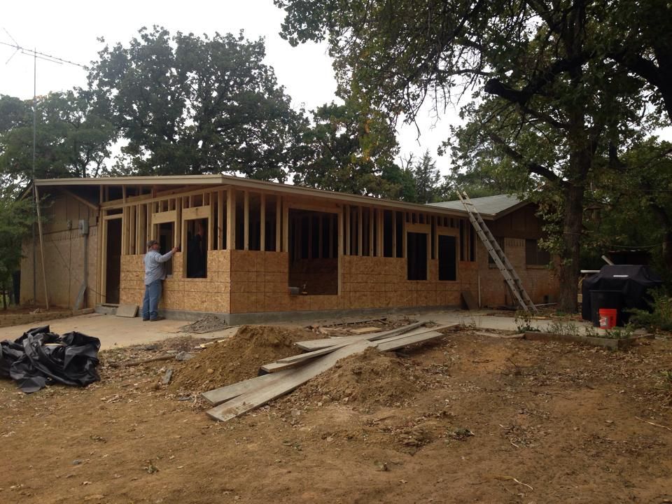 Construction of a one-story house. A worker is standing near the newly framed walls.