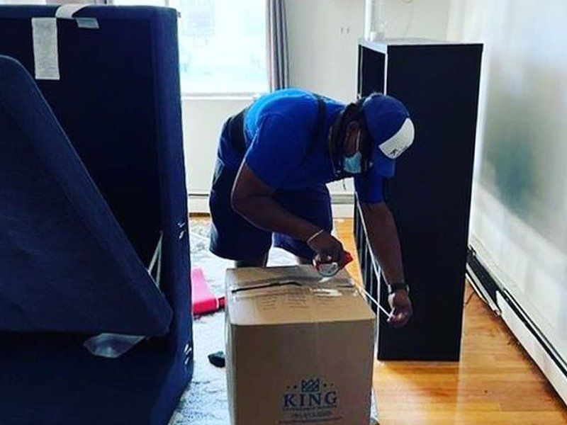 A man is kneeling down next to a box that says king on it.