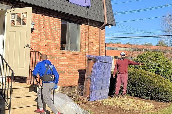 Two men are moving a couch into a house.