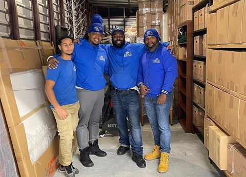 A group of men are posing for a picture in a warehouse.