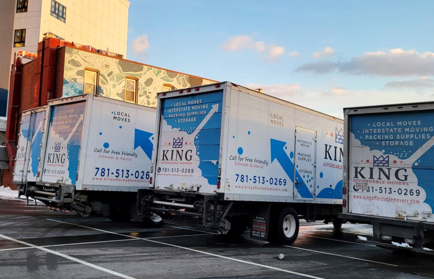 Three king moving trucks are parked in a parking lot