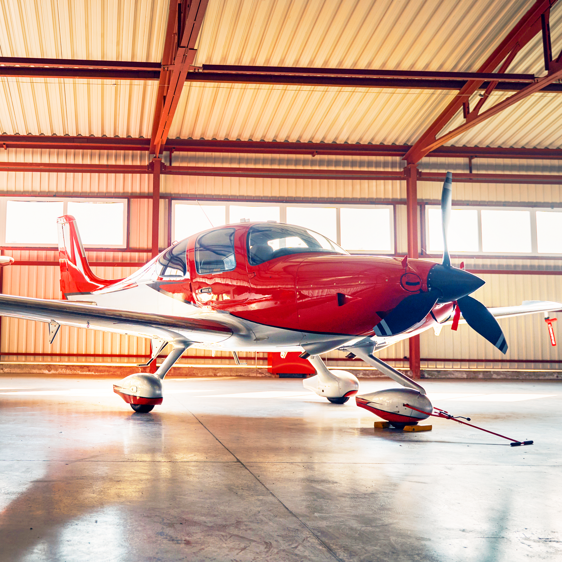 A small red airplane is parked in a hangar