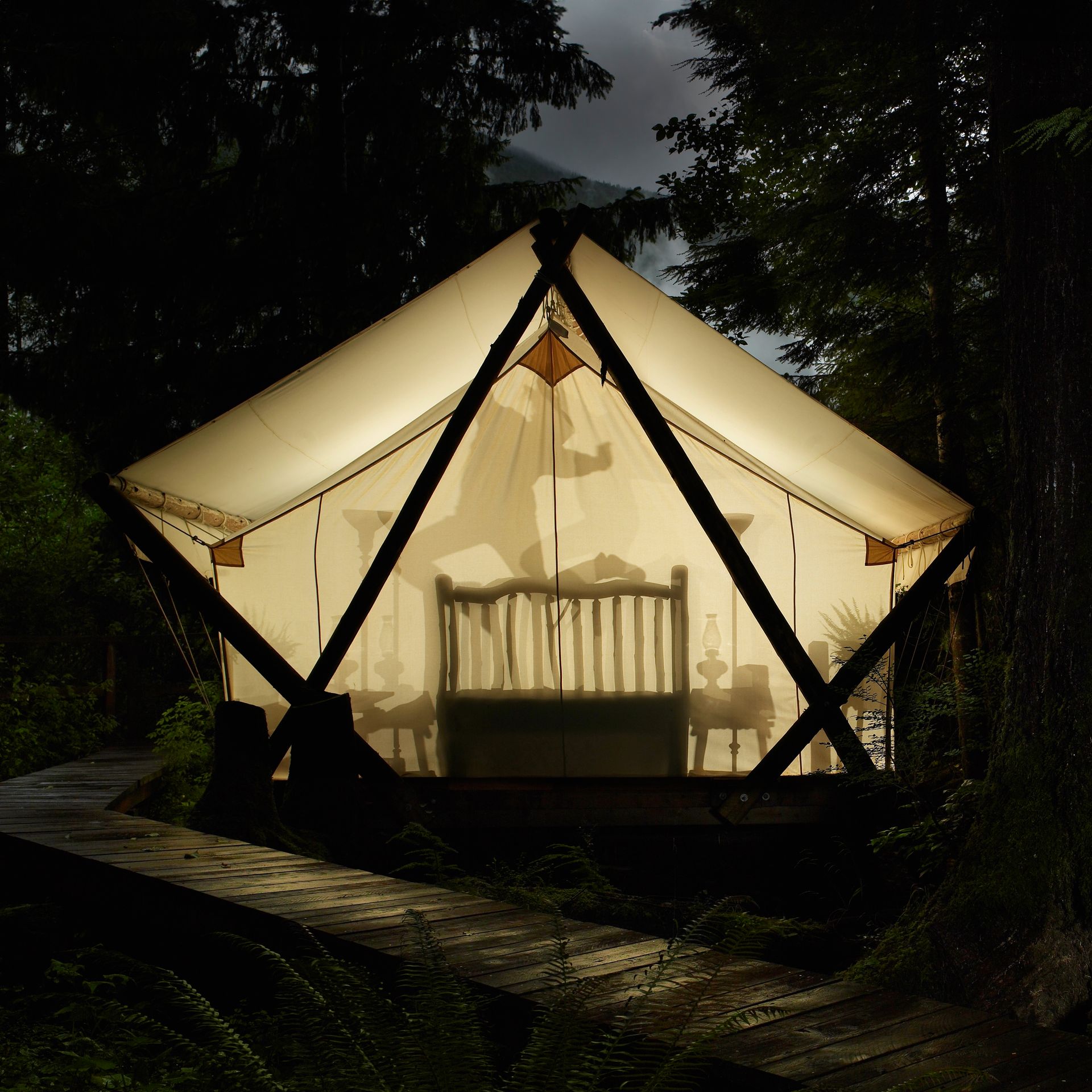 A tent with a bed inside of it is lit up at night