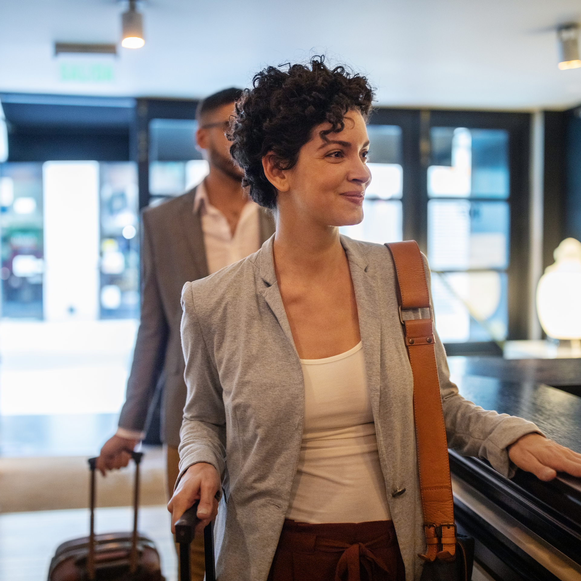 A woman is walking with a suitcase in a hotel lobby.