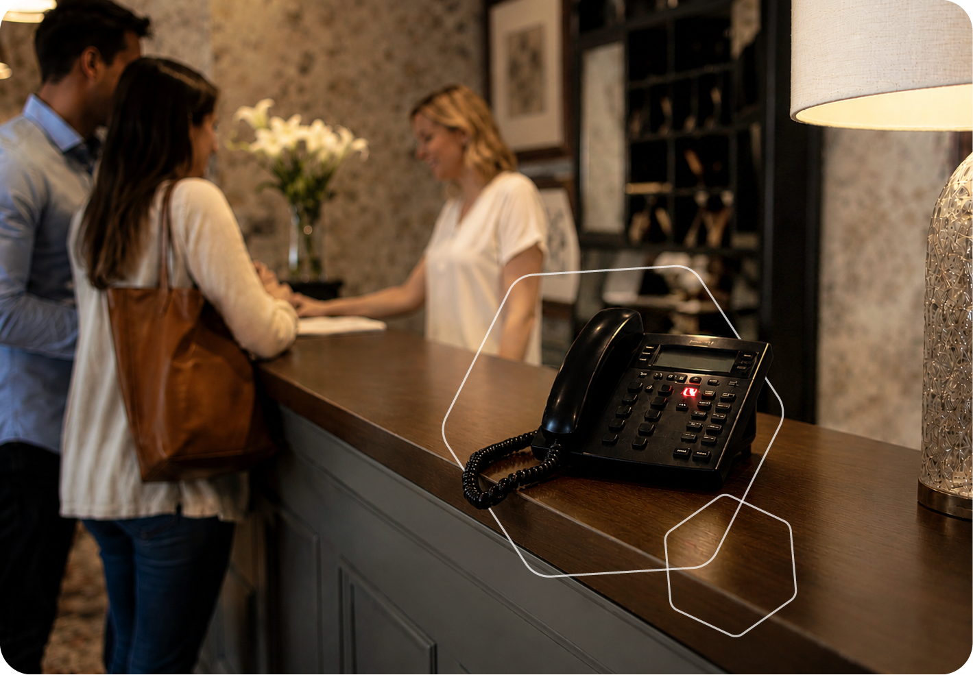 Hotel reception desk with guests checking in and a black office phone on the counter