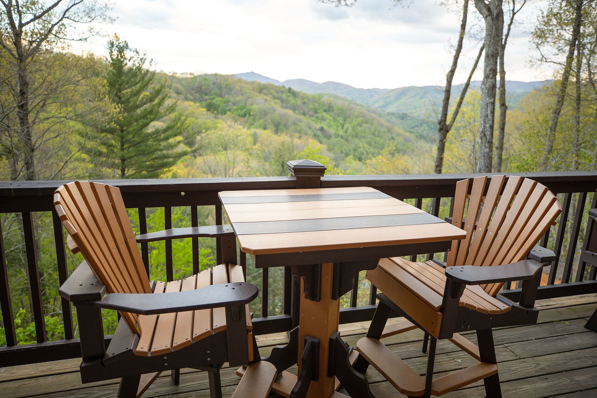 There is a table and chairs on the deck with a view of the mountains.