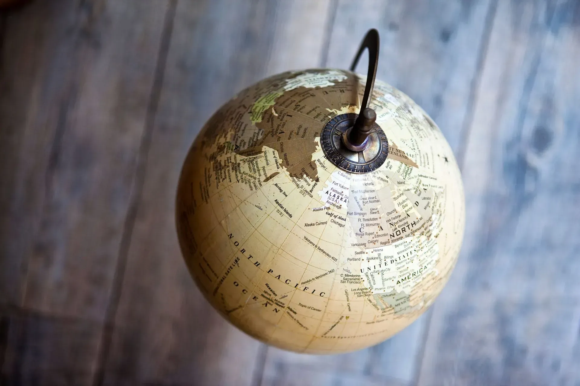A globe is hanging from a hook on a wooden floor.