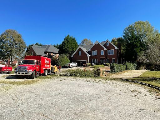 Red truck and workers in front of a brick house during landscaping or yard work