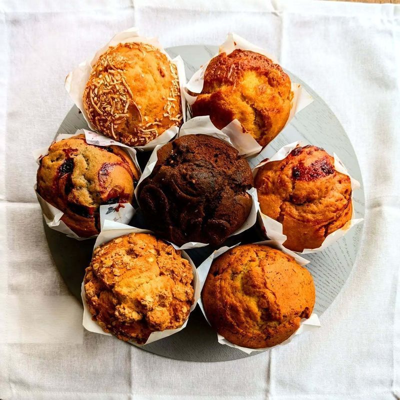 Assorted muffins on a white cloth, arranged on a round gray plate.