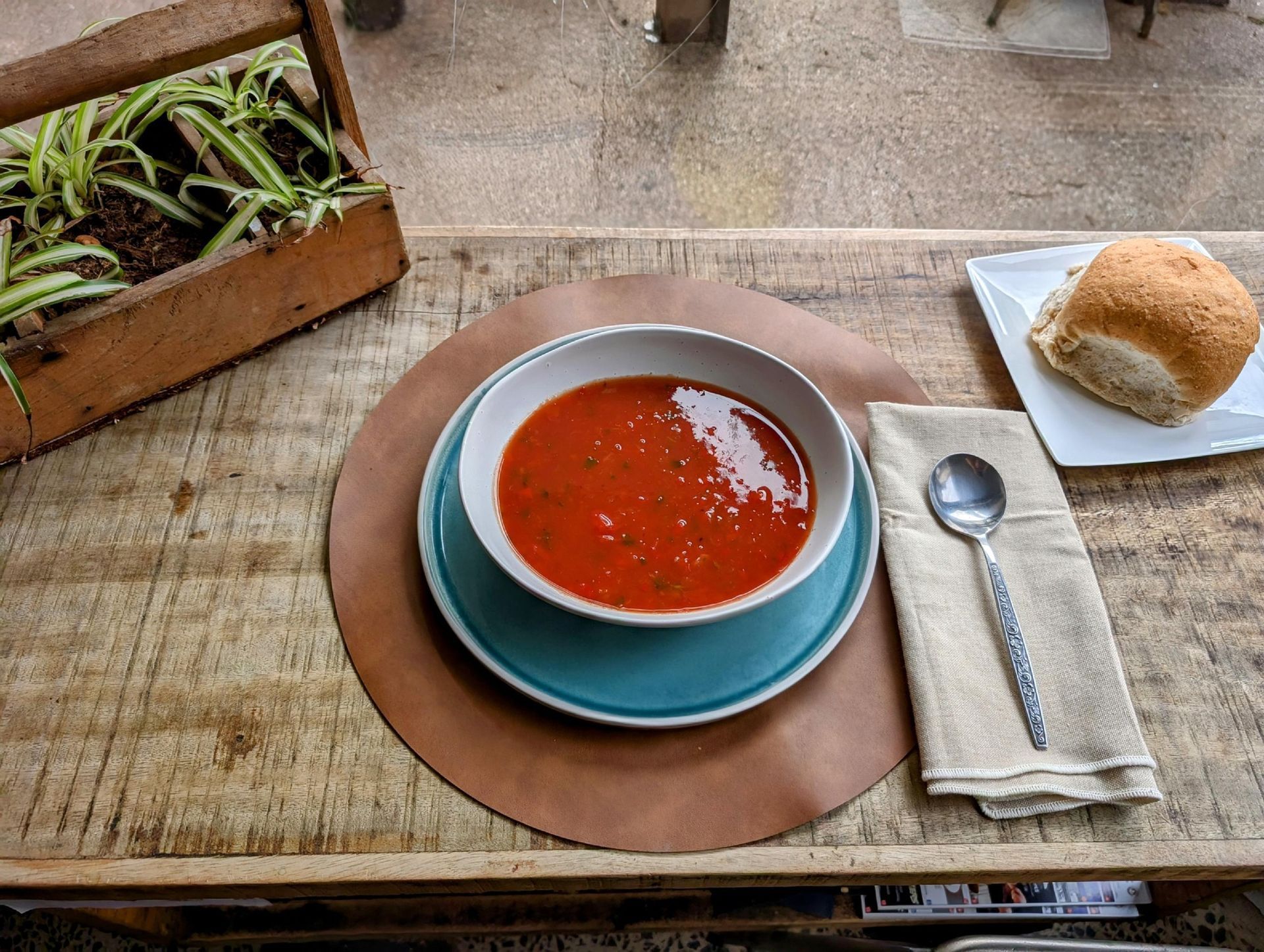 Bowl of red soup on a cafe table with bread, spoon, and napkin on a tray