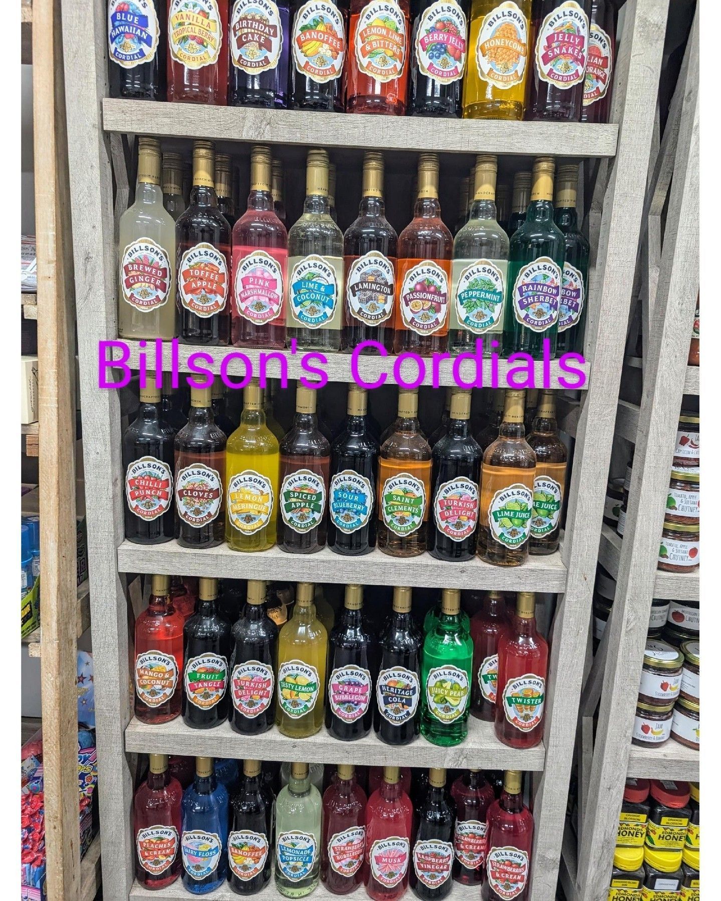 Shelf of colorful bottled cordials with “Bisons Cordials” sign in a store aisle