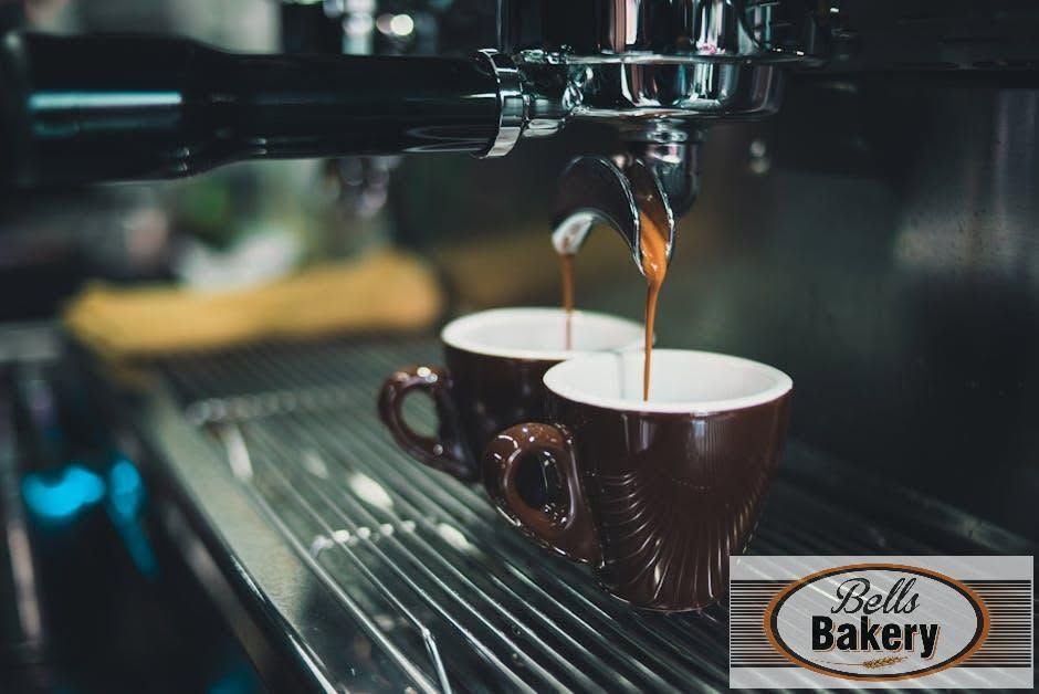 Coffee pouring into two brown mugs from an espresso machine, with a “Bell Bakery” logo in the corner