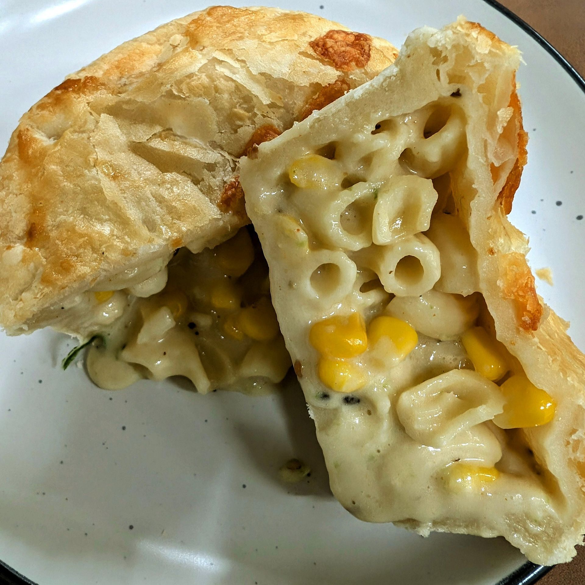Cut open pastry filled with creamy macaroni and cheese on a plate