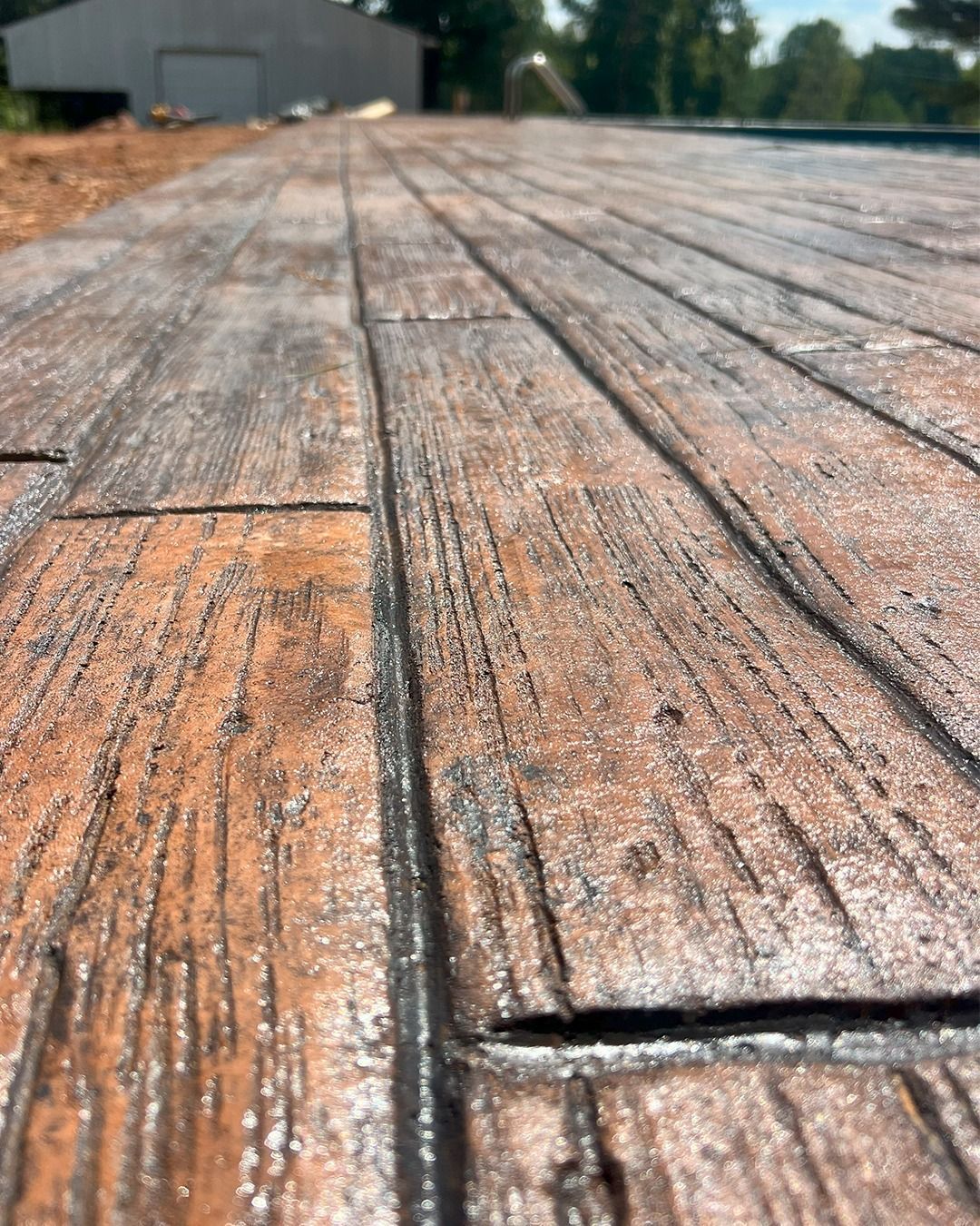 Close-up of weathered wooden decking with orange-brown boards and a blurred building in the distance