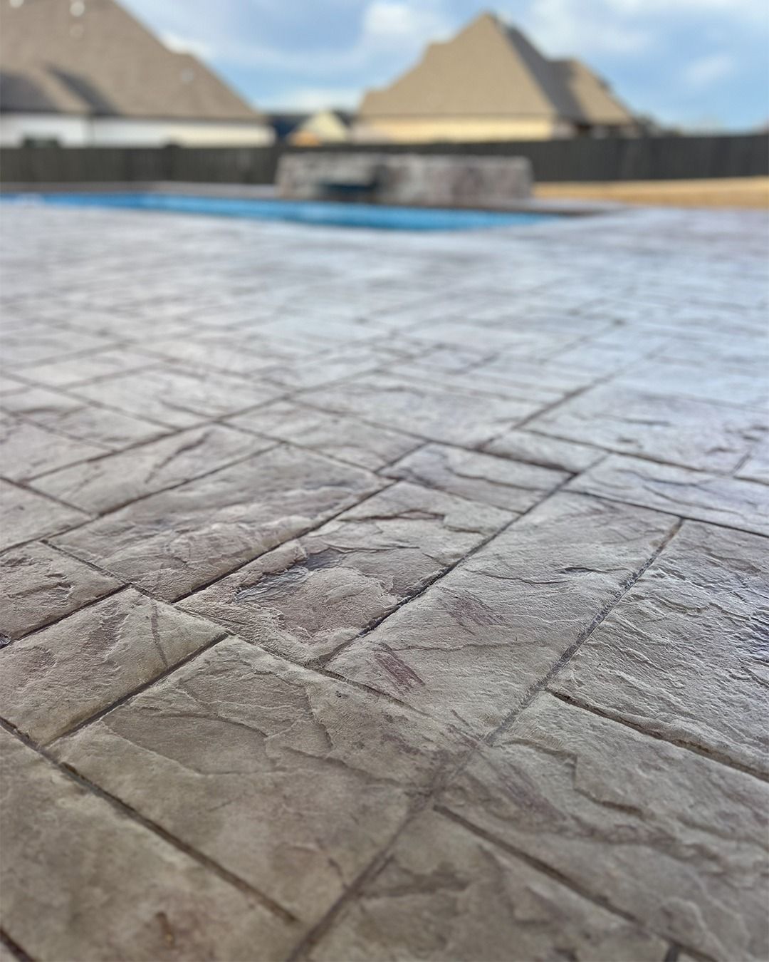 Stone-patterned plaza pavement with pyramids blurred in the background under a blue sky