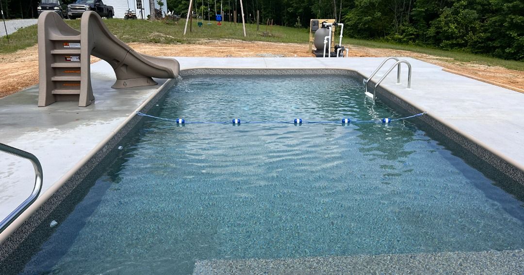 Long rectangular outdoor swimming pool with a slide and diving board at the far end