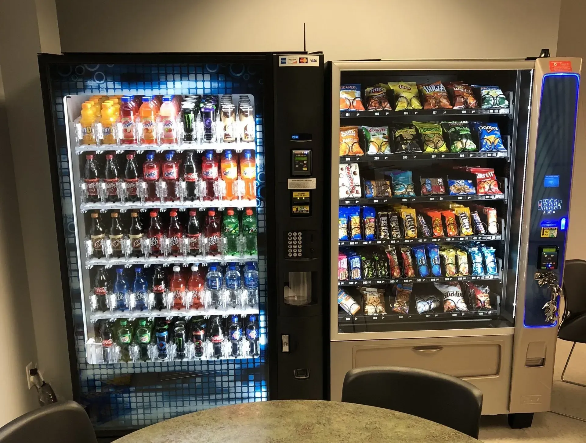 Two vending machines are sitting next to each other in a room.