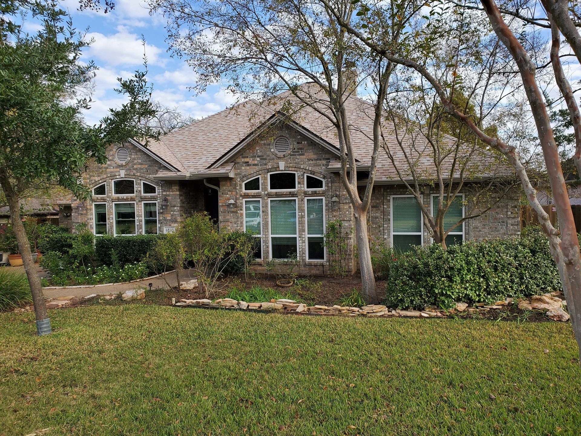 A large brick house with a lot of windows and trees in front of it.