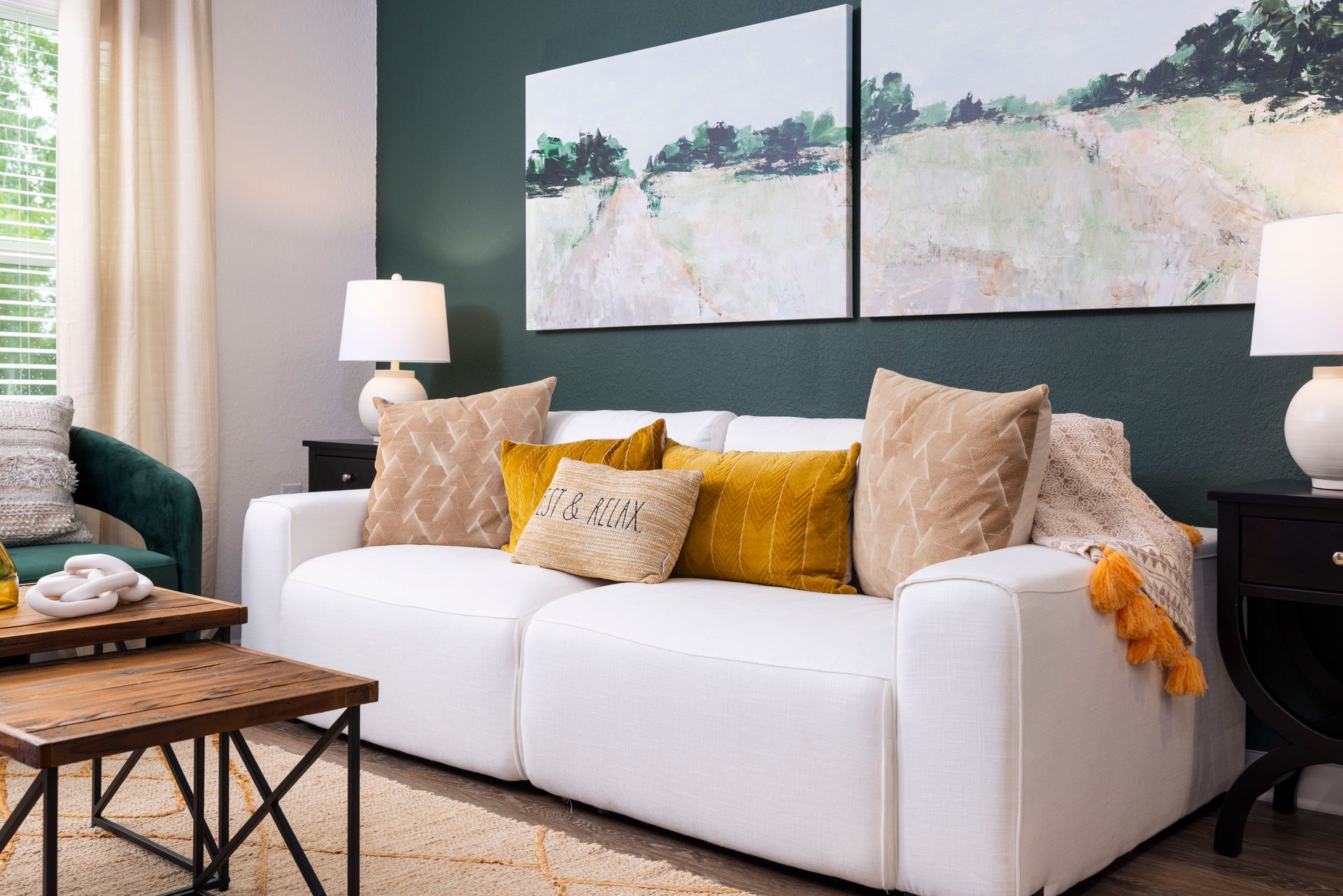 A living room with a couch, two coffee tables, wall art and plants.