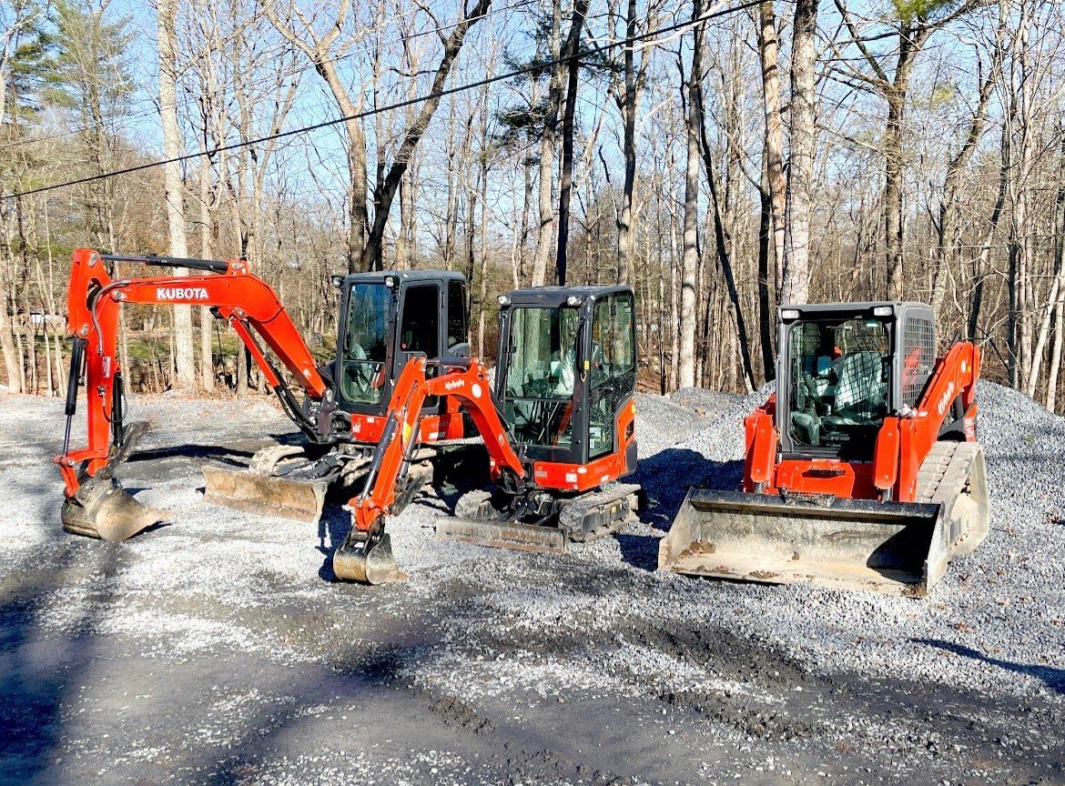 Three excavators are parked next to each other in a parking lot.