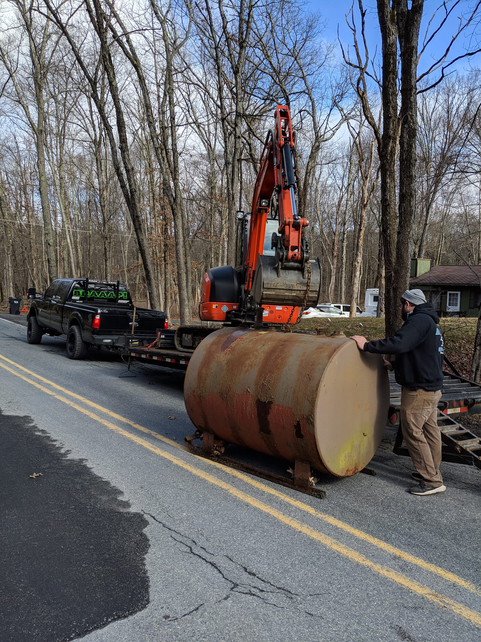 A man is standing next to a large barrel on the side of a road.