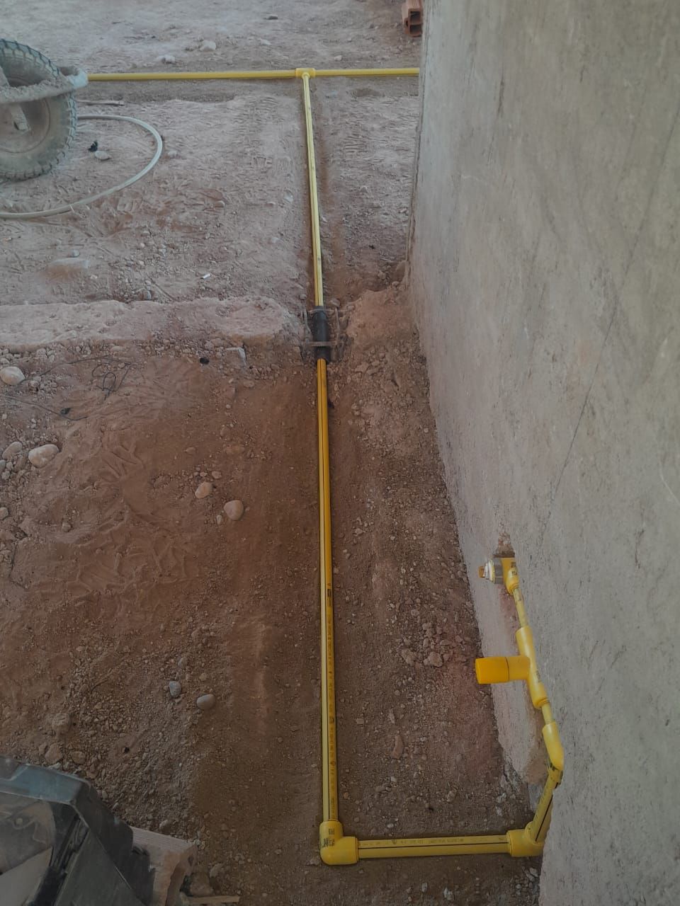 Instalación de una tubería de gas amarilla a lo largo de una pared en un piso de construcción polvoriento.