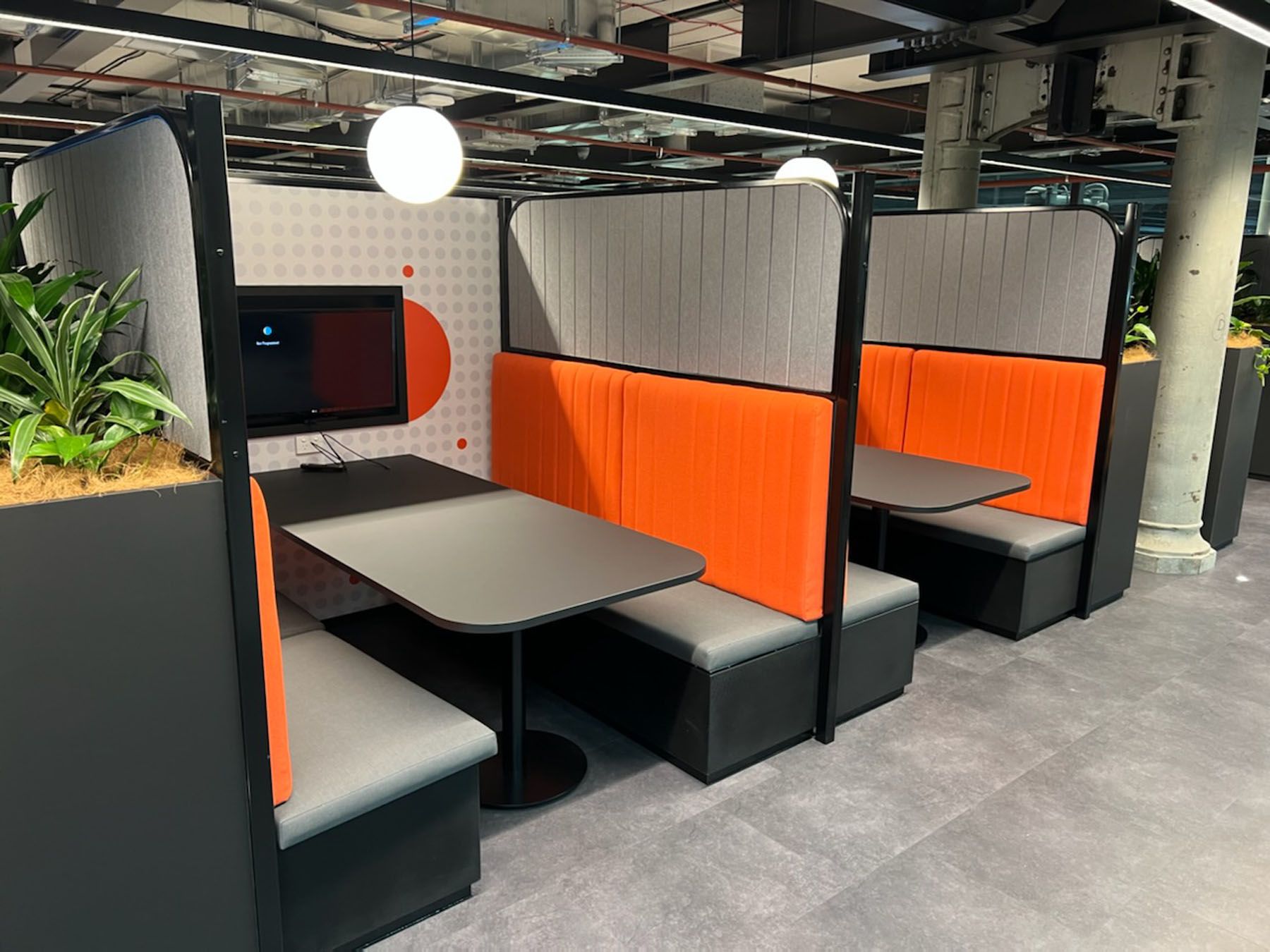 Booth seating in a modern office. Orange and gray upholstery with a table.