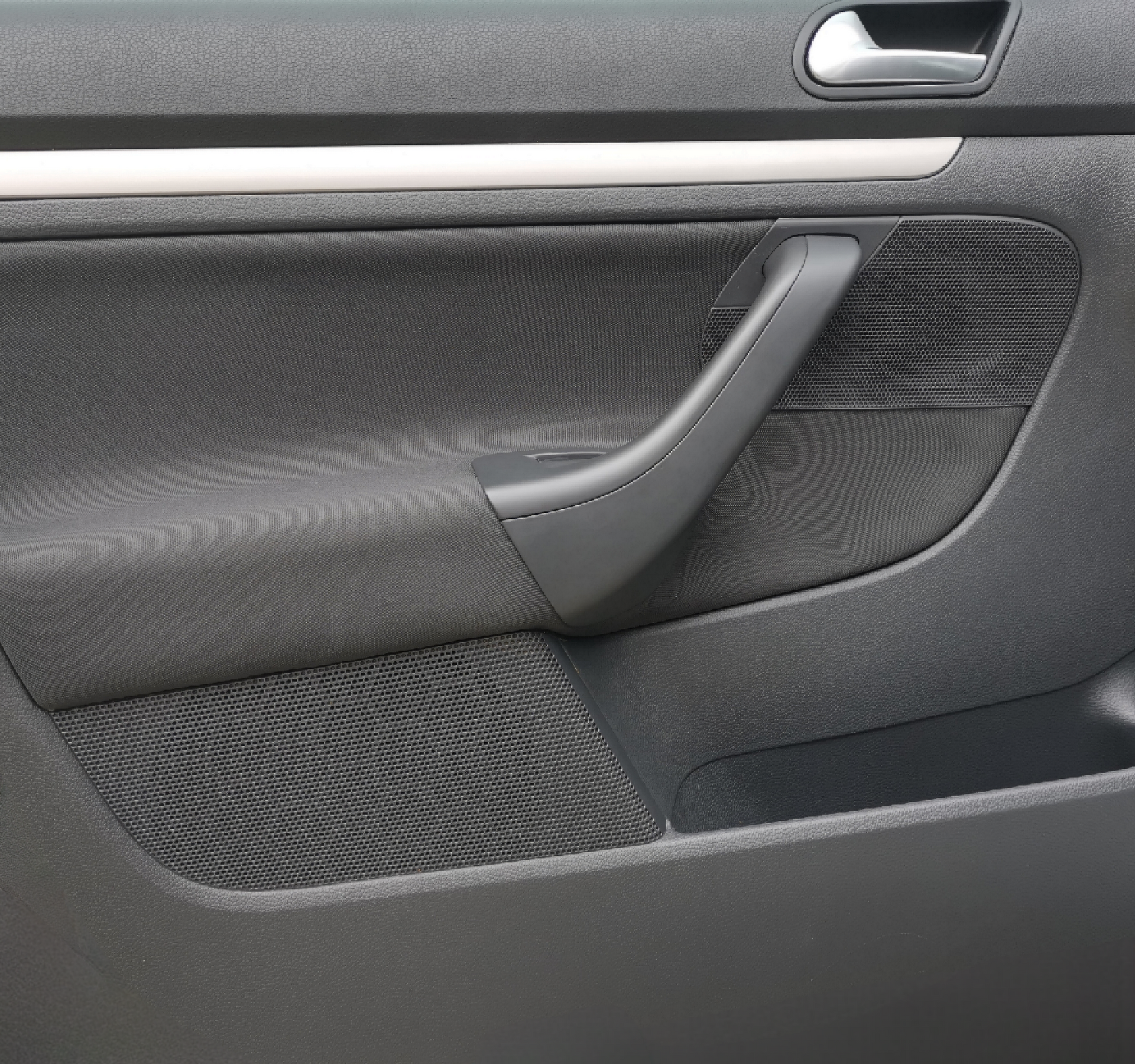 Car door interior, gray textured plastic with a black handle, silver trim, and a mesh pocket.