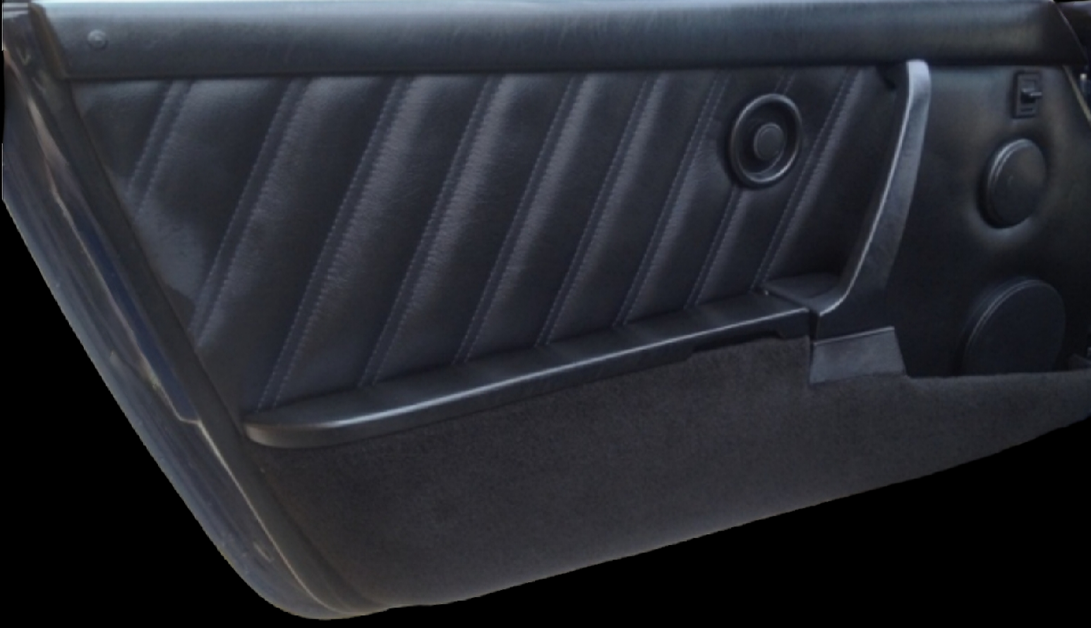Black car door panel with textured, stitched leather and speaker.