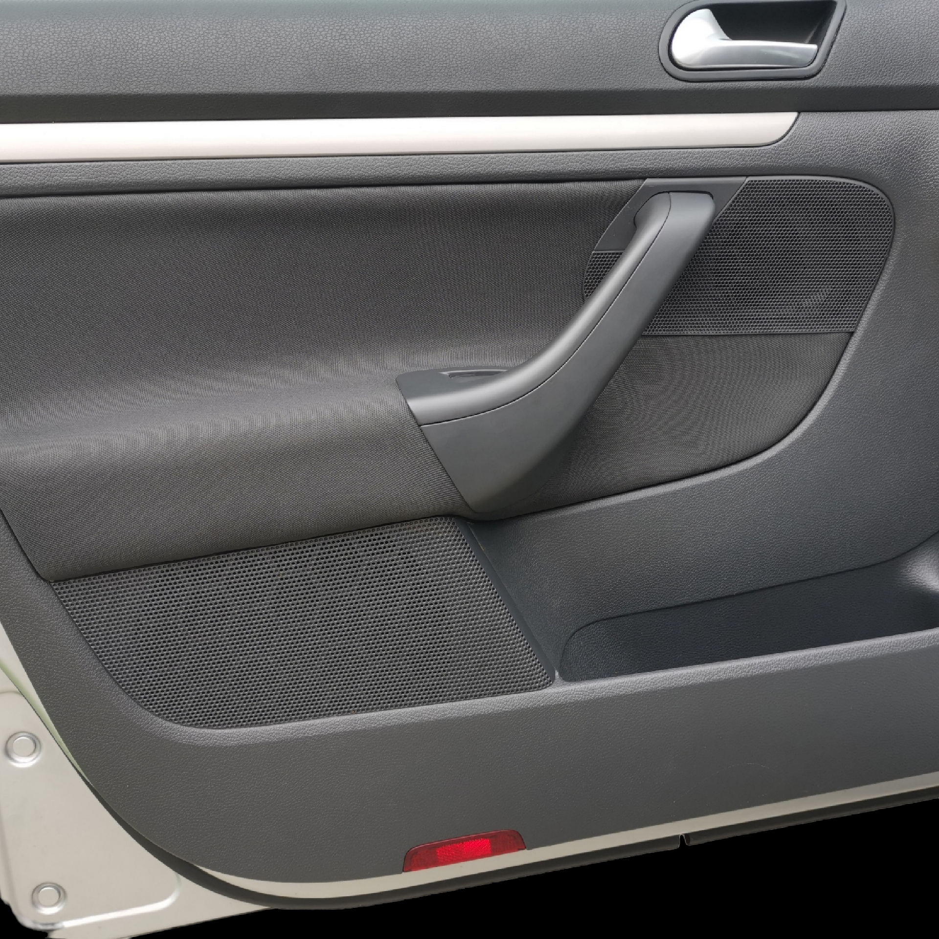 Black car door interior with handle, fabric panel, and red light.