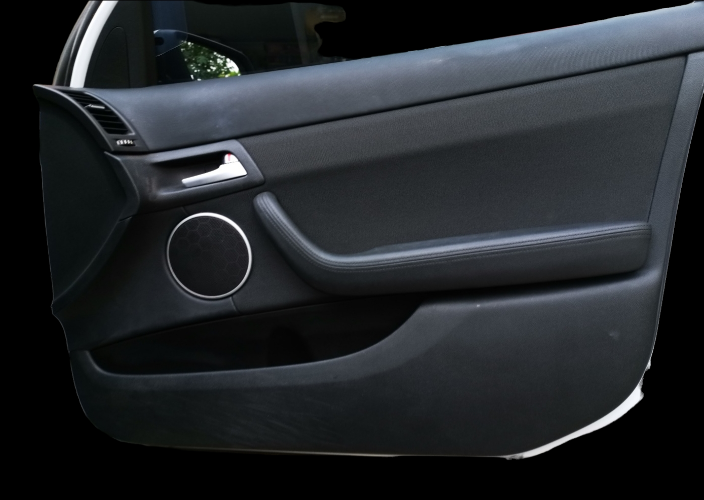Black car door panel with speaker, door handle, and armrest.