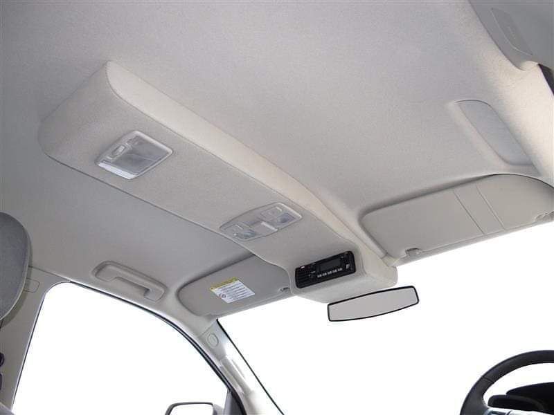Interior car ceiling view showing lights, sun visor, rear view mirror, and a radio.