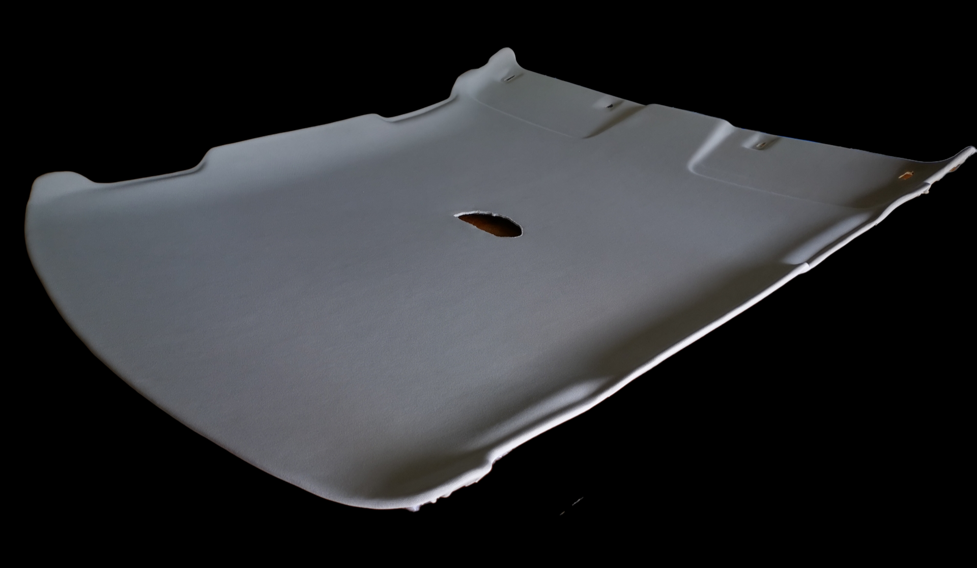 Gray car headliner with a hole, against a black background.