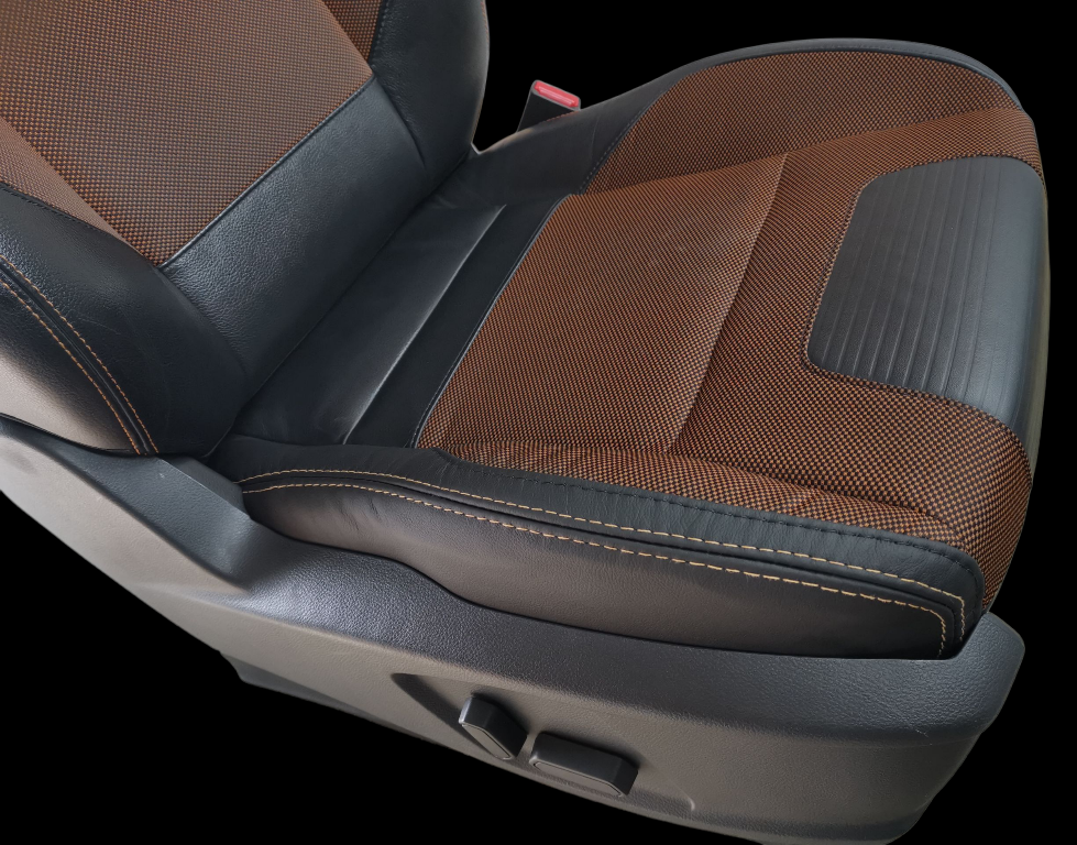 Brown and black car seat with textured fabric and stitching, power adjustment controls.