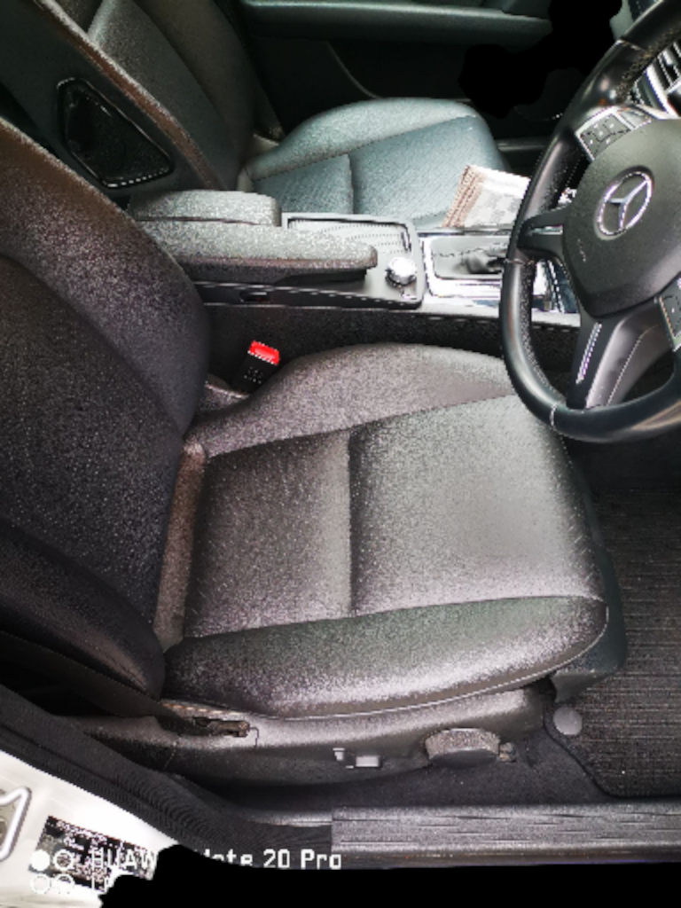 Black leather car seat and dashboard. Steering wheel visible.