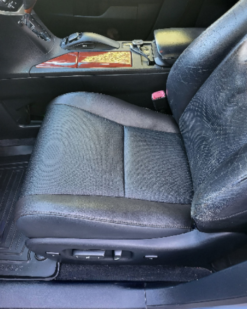 Black leather car seat with adjustable controls, wood trim in the background.