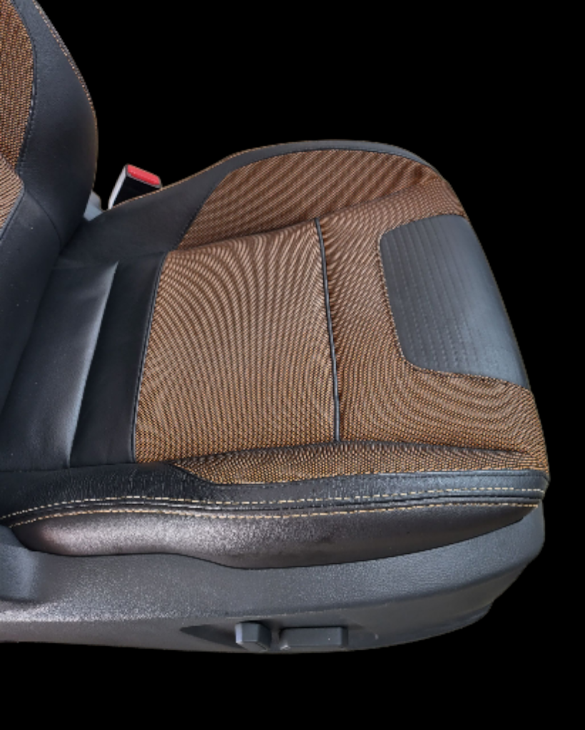 Black and brown car seat with fabric and leather accents, set against a black background.