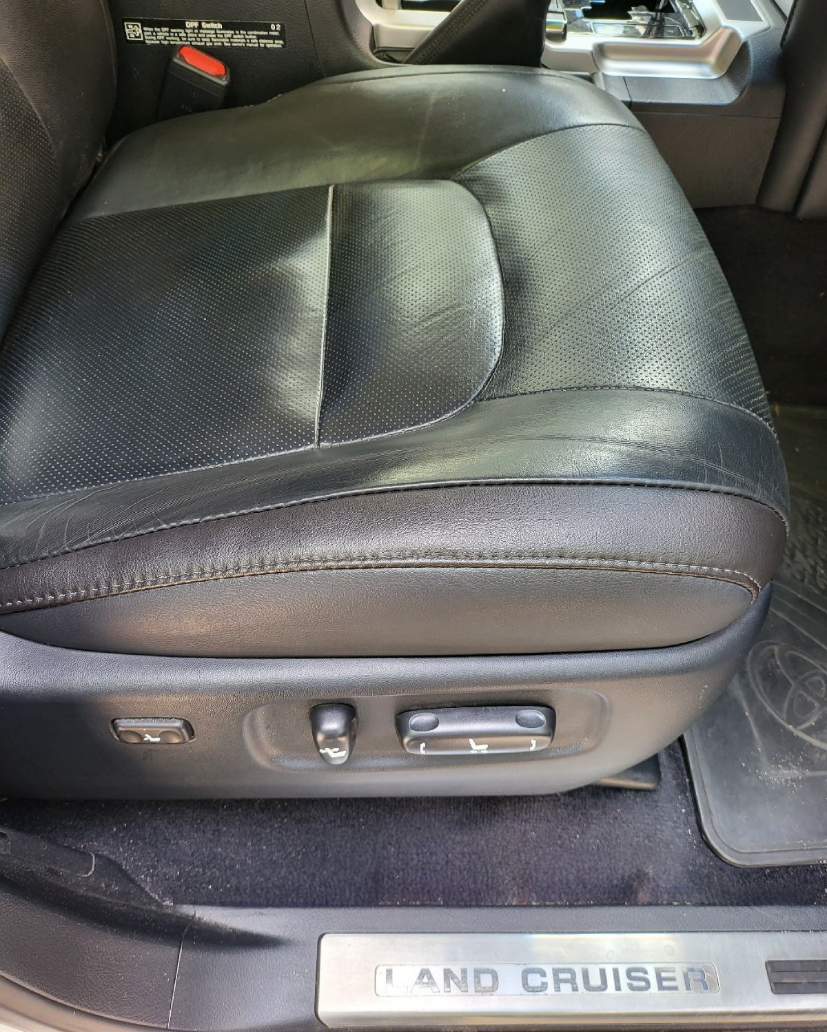 Black leather car seat with power adjustments, labeled